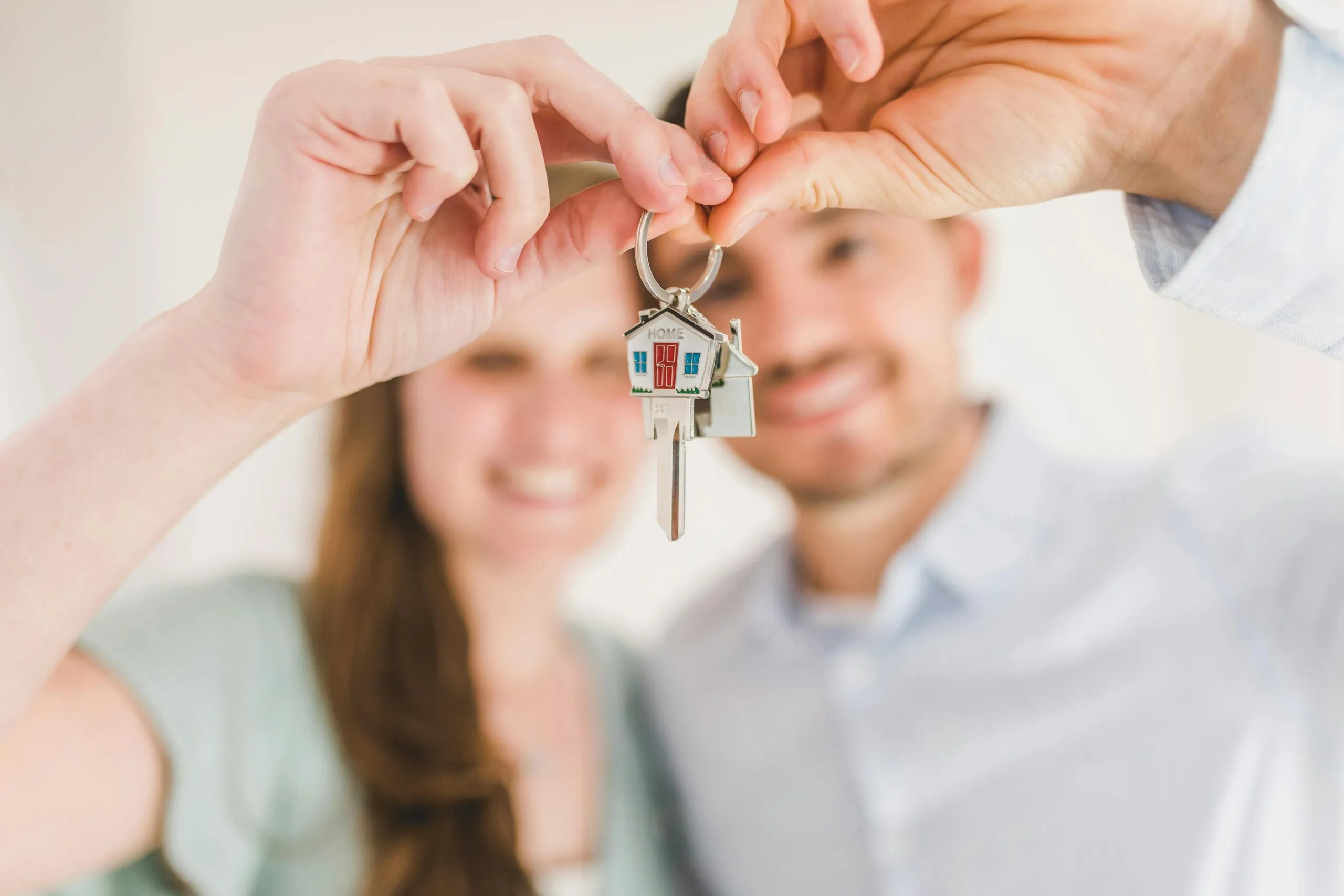 Couple forming a heart shape with their hands around a house-shaped key chain