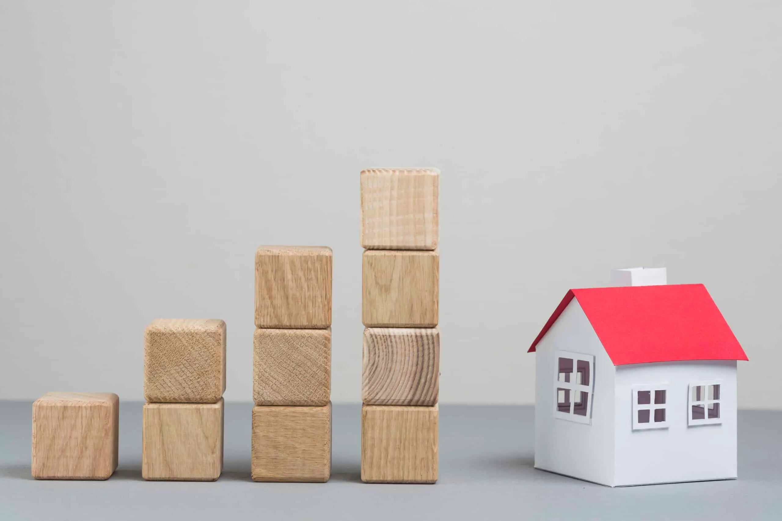 Wooden blocks stacked in increasing height beside a small model house